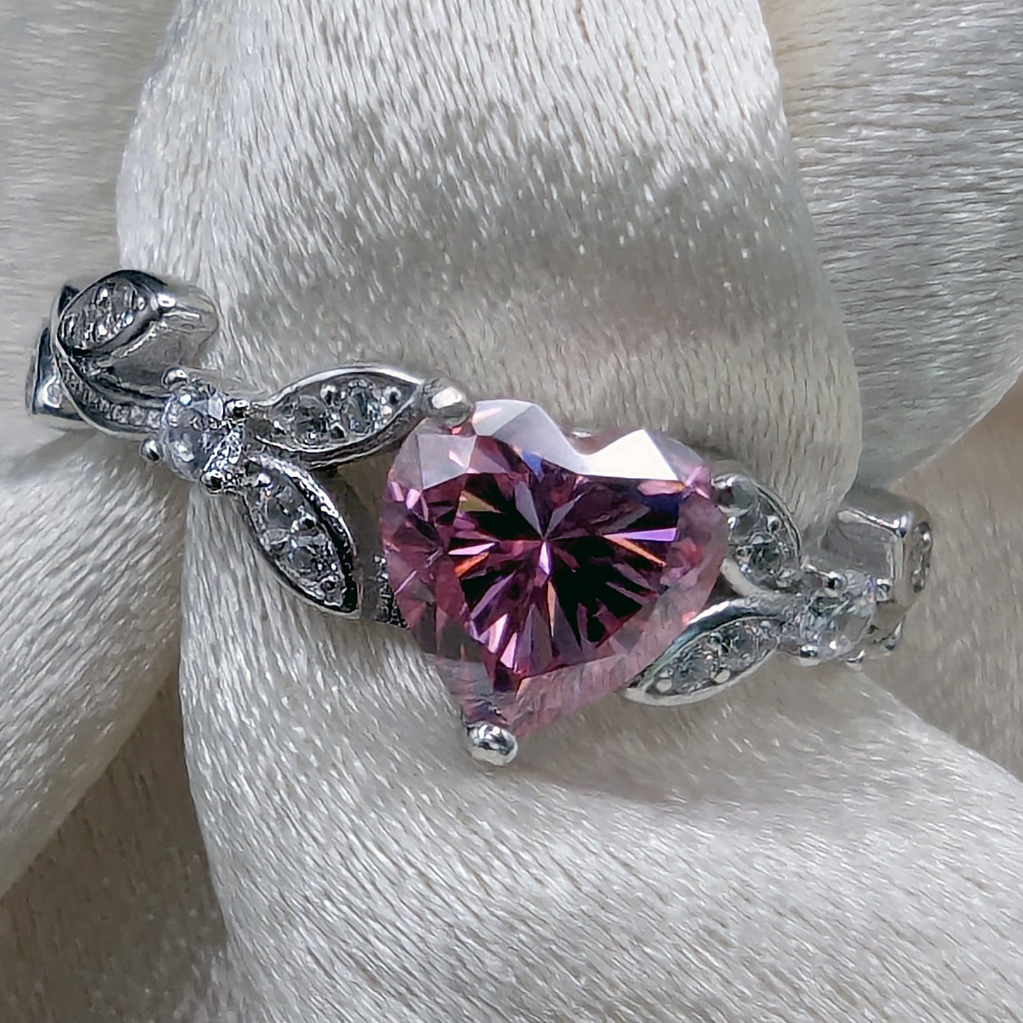 Silver bracelet with a heart-shaped pink gemstone on a white fabric background