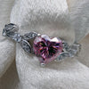 Silver bracelet with a heart-shaped pink gemstone on a white fabric background