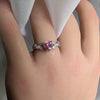 Ring with a pink gemstone on a person's finger against a white background