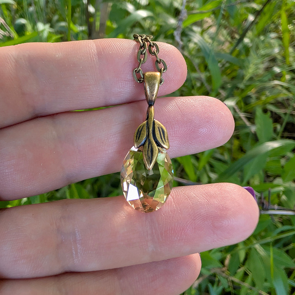 Hand holding a Swarovski golden shadow crystal pendant 