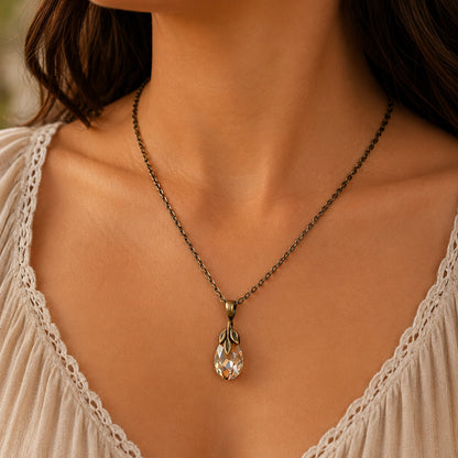 Necklace with a teardrop Swarovski crystal golden shadow pendant worn by a person in a light-colored top.