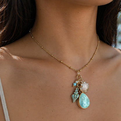 Necklace with turquoise pendant and shell charm worn by a person