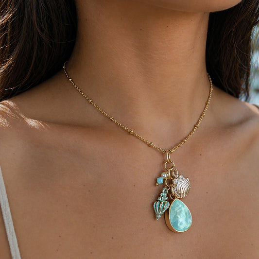 Necklace with turquoise pendant and shell charm worn by a person
