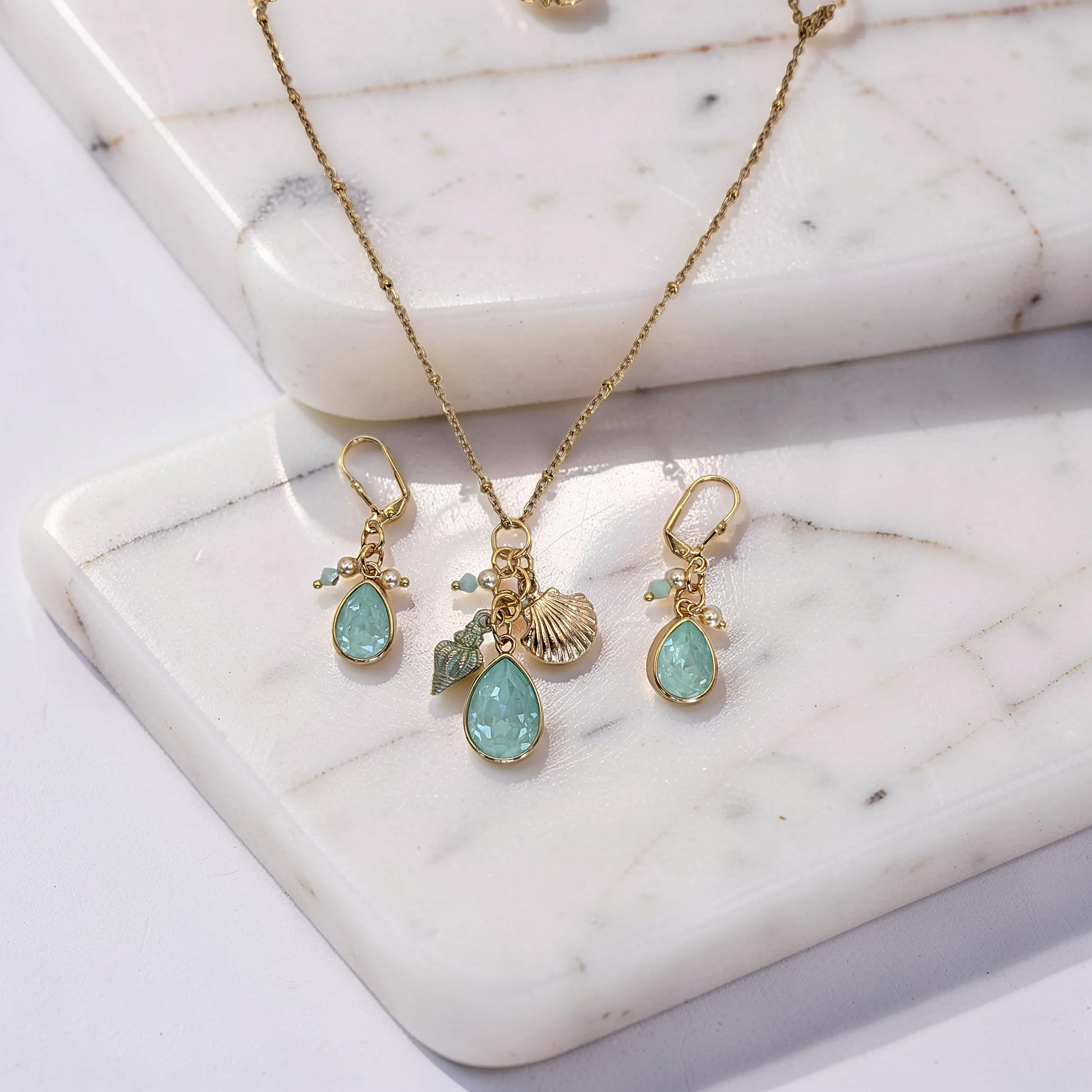 Gold necklace with pendant and matching earrings on a marble surface