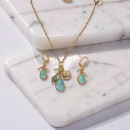 Gold necklace with pendant and matching earrings on a marble surface