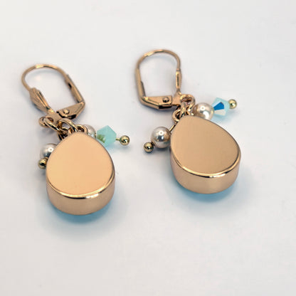 Gold teardrop-shaped earrings with small beads on a light gray background