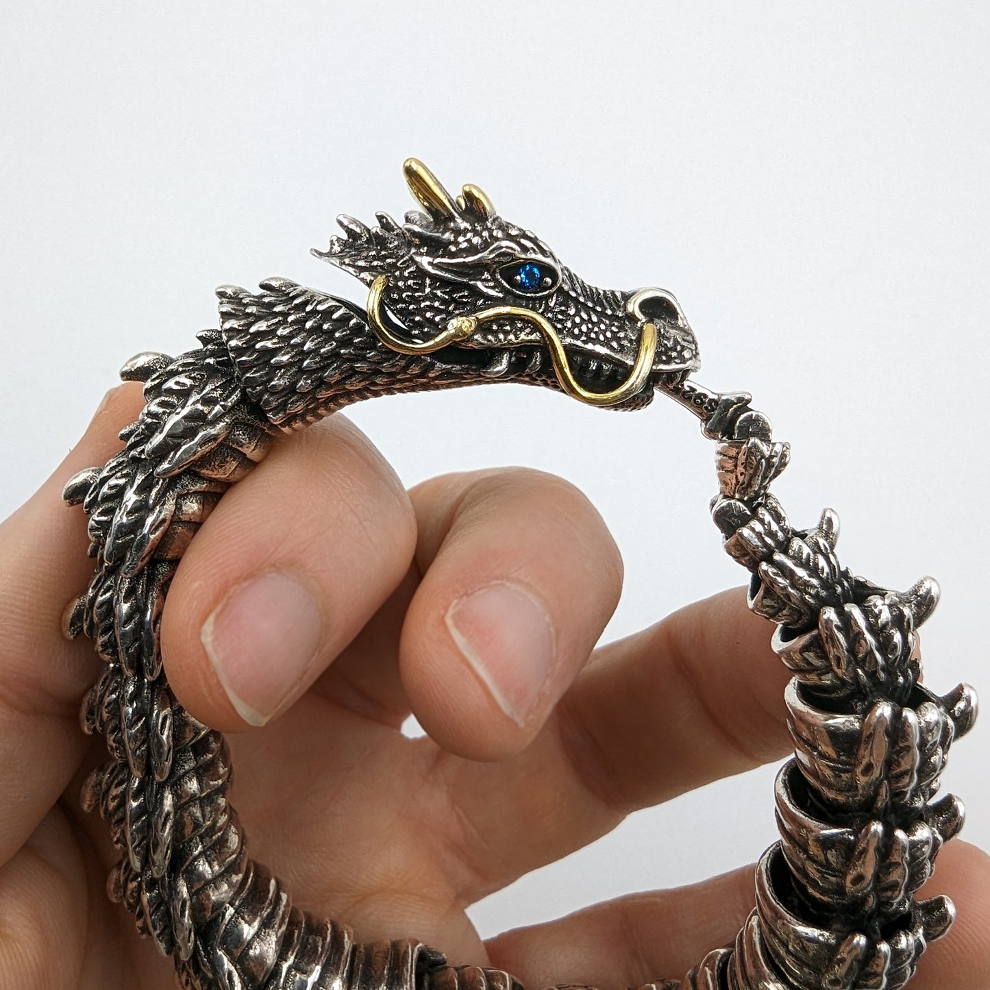 Silver dragon bracelet on a hand with a plain background
