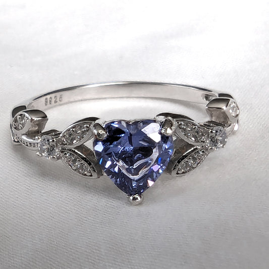 Silver ring with a Tanzanite gemstone and diamonds on a light gray background