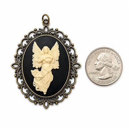 Decorative vintage angel cameo pendant necklace with intricate gold frame next to a U.S. quarter dollar coin on a white background.  Victorian spiritual jewelry.