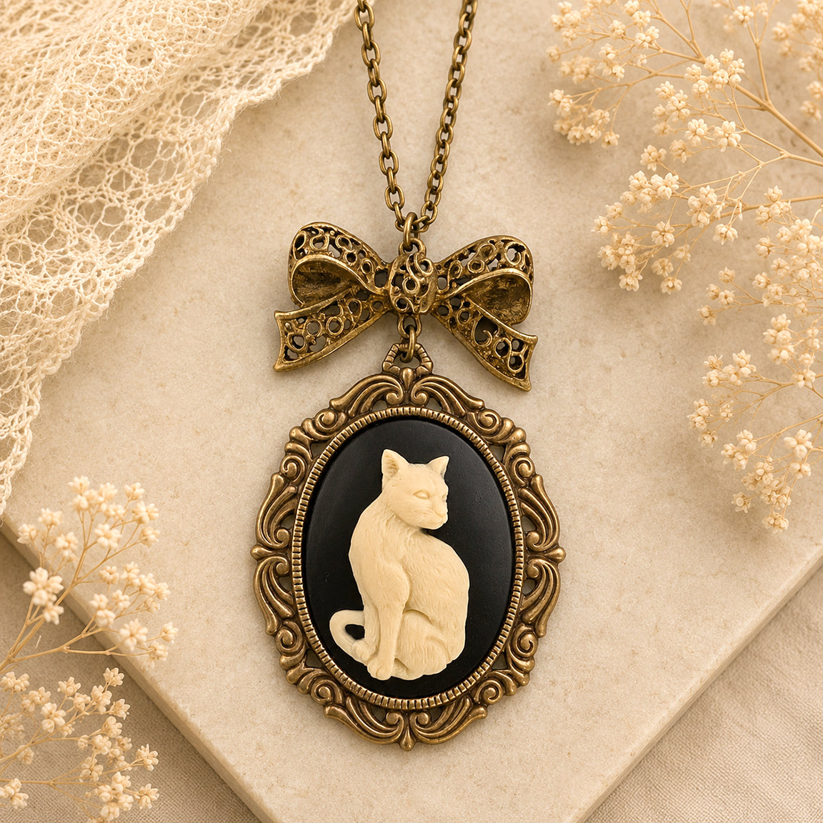 Vintage-style necklace with a cat cameo pendant on a textured surface with lace and flowers.  Cat lover jewelry gift