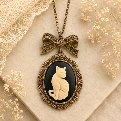 Vintage-style necklace with a cat cameo pendant on a textured surface with lace and flowers.  Cat lover jewelry gift
