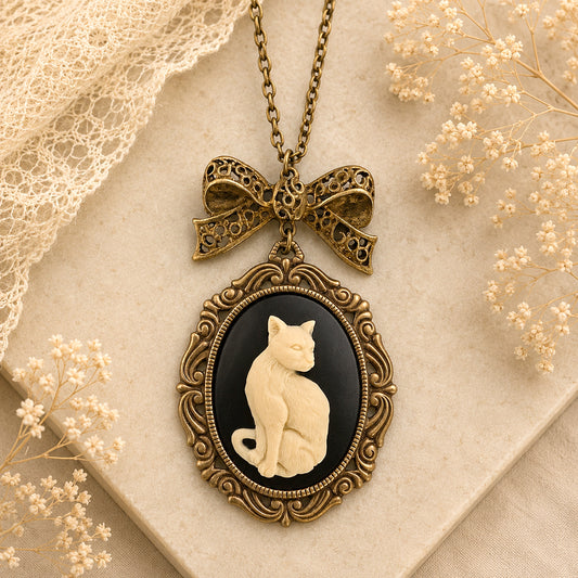 Vintage-style necklace with a cat cameo pendant on a textured surface with lace and flowers.  Cat lover jewelry gift
