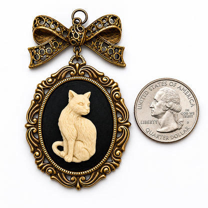 Decorative pendant with a cat silhouette and gold bow, next to a US quarter dollar coin for scale.