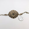 Bronze brass floral bracelet next to a quarter on a white background