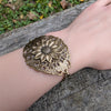 Brass sunflower floral bracelet on a wrist with a natural background