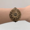 vintage Bronze sunflower floral bracelet on a wrist against a neutral background
