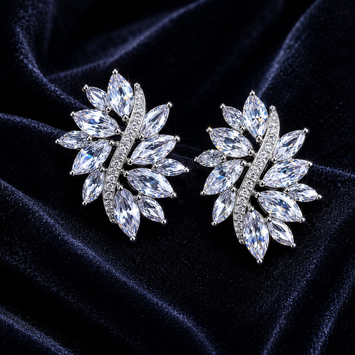 Pair of silver earrings with cubic zirconia gemstones on a dark blue velvet background