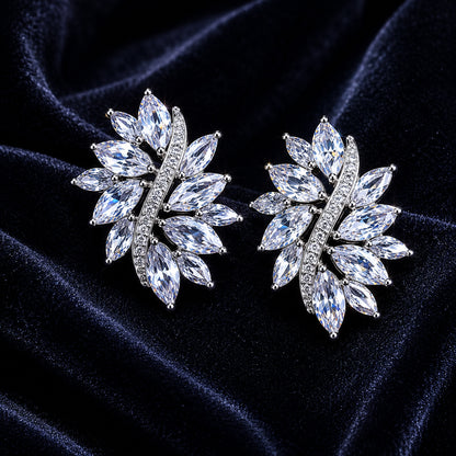 Pair of silver earrings with cubic zirconia gemstones on a dark blue velvet background