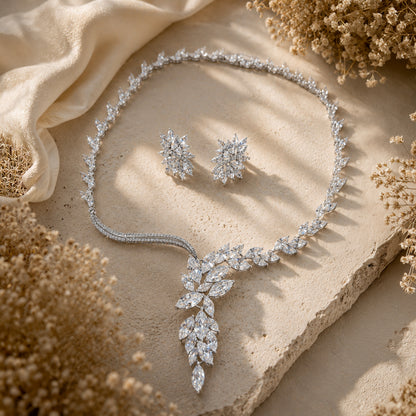Silver cubic zirconia bridal jewelry set with necklace and earrings on a textured surface with dried flowers.