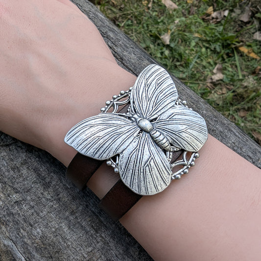 Silver butterfly bracelet on a wrist with a natural background