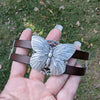 Butterfly-shaped bracelet on a hand with grass background