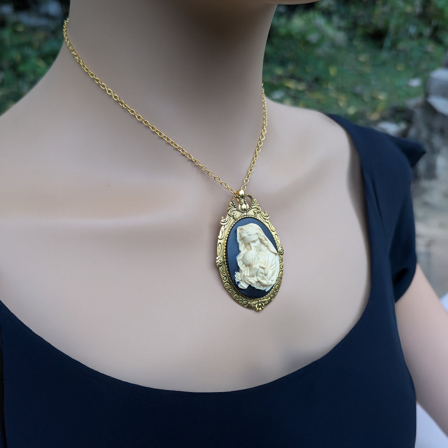 Virgin Mother Mary Kissing the Head of Baby Jesus Cameo brooch pendant being worn as a necklace on model
