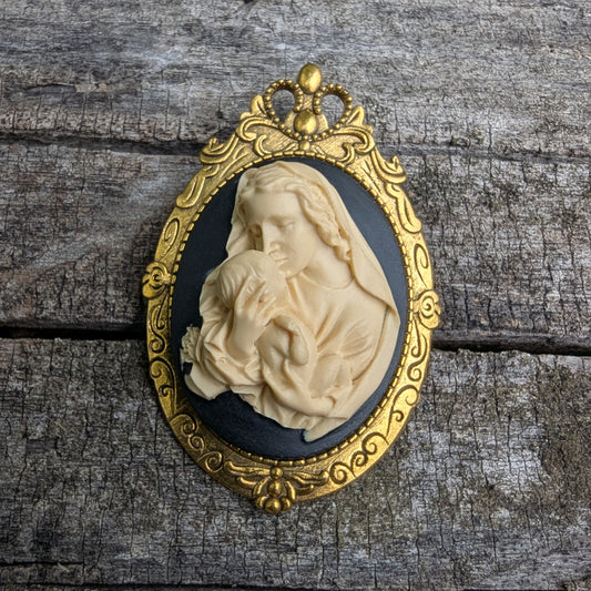Virgin Mother Mary Kissing the Head of Baby Jesus Cameo brooch pendant resting on a log
