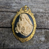 Virgin Mother Mary Kissing the Head of Baby Jesus Cameo brooch pendant resting on a log
