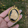 Virgin Mother Mary Kissing the Head of Baby Jesus Cameo brooch pendant being held in hand.