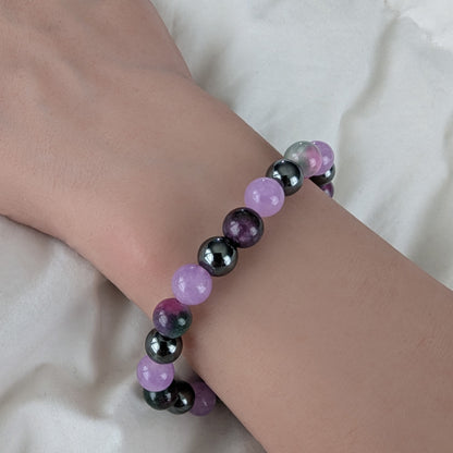 Bracelet with violet purple, Persian Jade and black hematite beads on a wrist against a white background