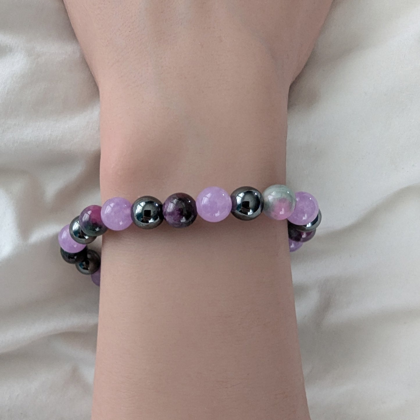 Bracelet with multicolored beads on a wrist against a neutral background