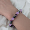 Bracelet with violet purple, Persian Jade and black hematite beads on a wrist against a white background