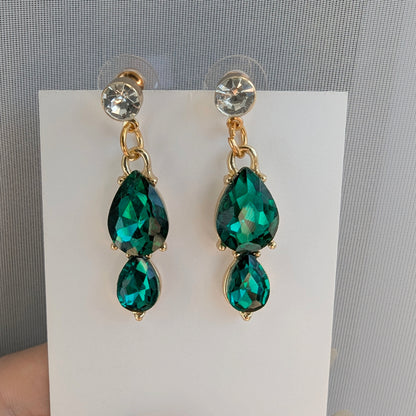 Green teardrop earrings with gold accents on a white card against a gray background
