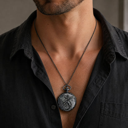 A close-up of a man wearing a dark metal gothic pocket watch necklace with an antique-style round pendant featuring an embossed dragon design, styled with a dark charcoal button-down shirt.