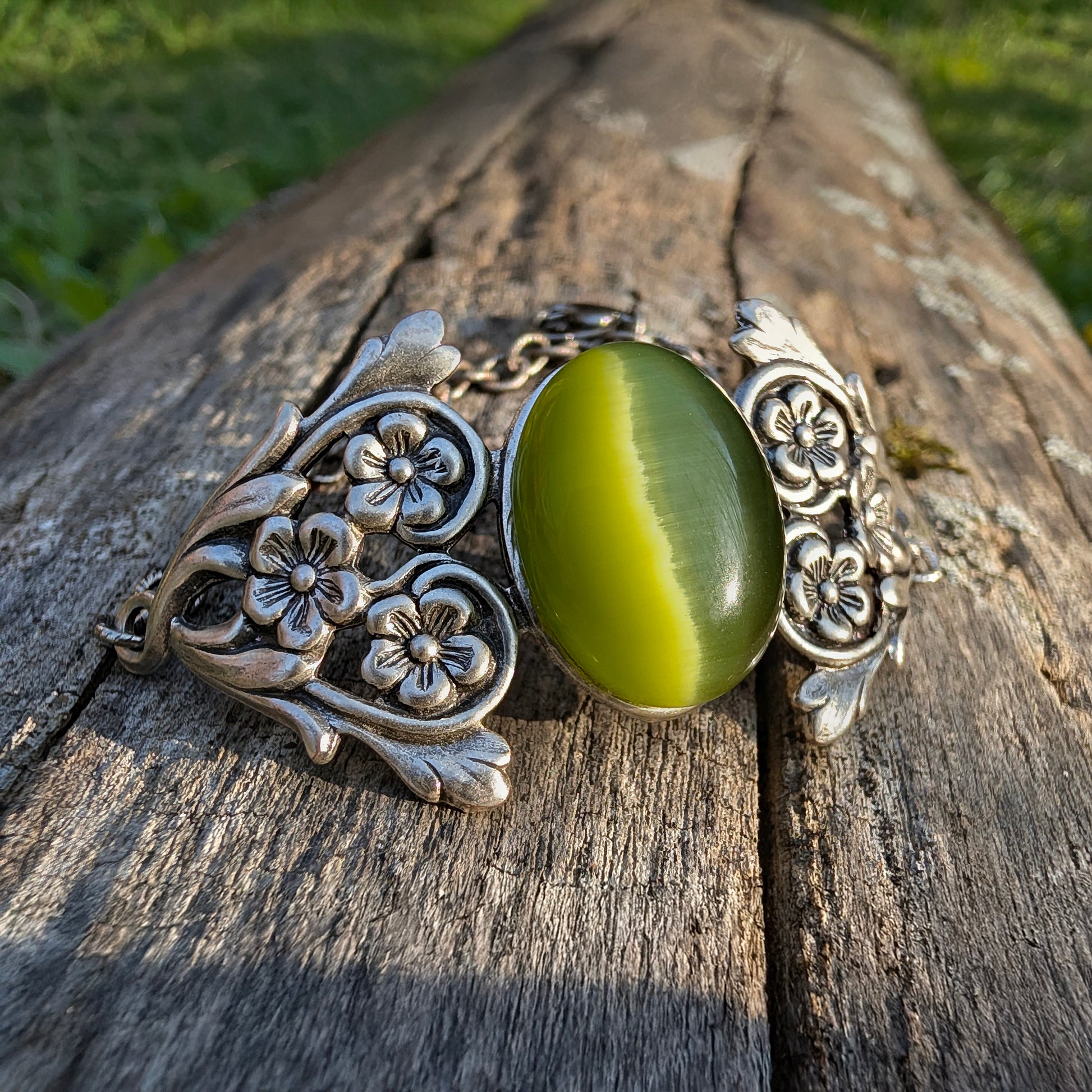 Olivine Cats Eye Sterling Silver Floral Green Glass Victorian Fairy Boho Bracelet, outside on a log.