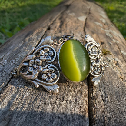 Olivine Cats Eye Sterling Silver Floral Green Glass Victorian Fairy Boho Bracelet, outside on a log.