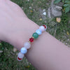 Holiday beaded natural stone stretch bracelet made with rose quartz, green aventurine and white howlite beads, accented by red Swarovski crystals on a wrist against a natural background
