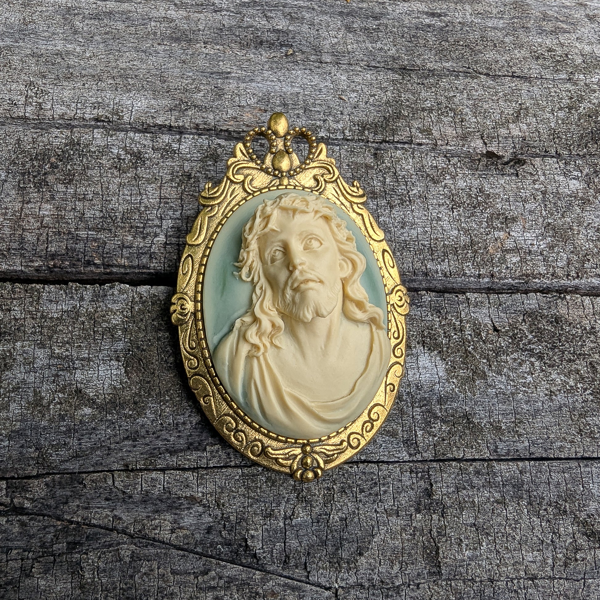 Gold-framed pendant with a 3D portrait of Jesus on a wooden surface