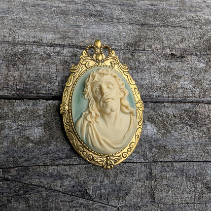 Gold-framed pendant with a 3D portrait of Jesus on a wooden surface
