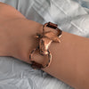 Copper bracelet with horse head design on a wrist against a light fabric background