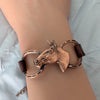 Bronze horse head and horseshoe bracelet on a wrist against a light background