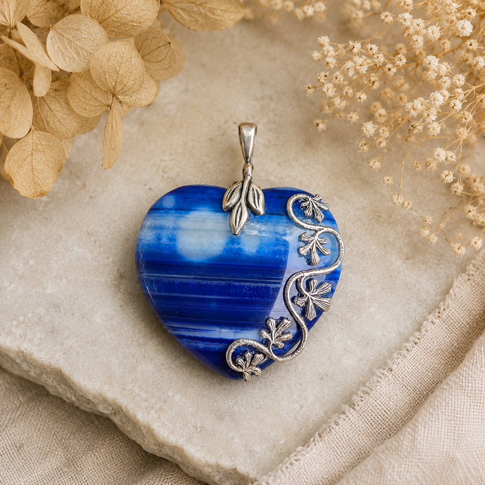 Natural blue striped agate heart pendant featuring sterling silver plated brass accents displayed on a nuetral background. Nature inspired Boho Jewelry.