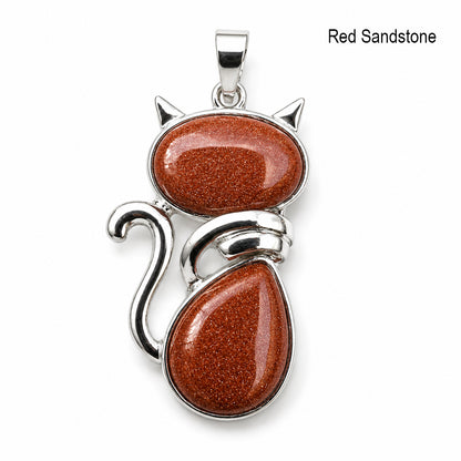 Cat-shaped pendant with red sandstone stones and silver accents on a white background