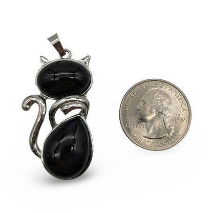 Black onyx stone cat-shaped pendant next to a quarter for scale on a white background