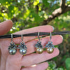 silver and gold pearl drop earrings with rhinestone flowers outside with hand