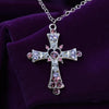 Decorative cross necklace with pink , purple and clear stones on a purple background