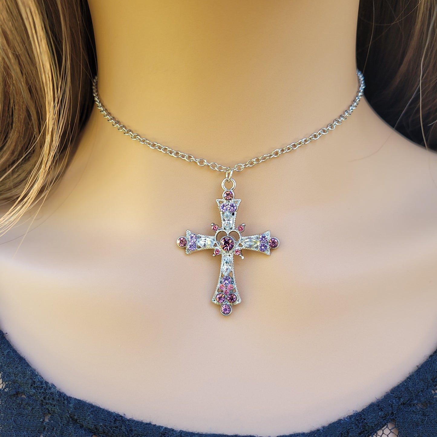 Silver cross necklace with colorful stones on a model