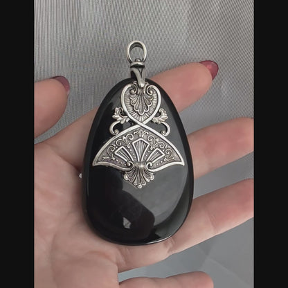 Black druzy stone pendant with silver decorative Art Dedco design held in a hand