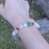 Holiday beaded natural stone stretch bracelet made with rose quartz, green aventurine and white howlite beads, accented by red Swarovski crystals on wrist