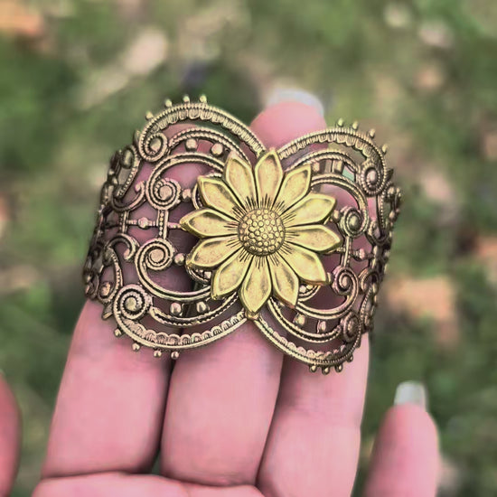 Vintage style brass floral sunflower statement bracelet against hand